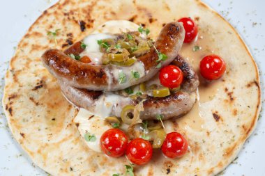 Domates ve baharatlı tortillada ızgara sosis.