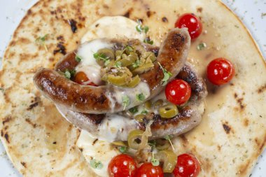 Domates ve baharatlı tortillada ızgara sosis.