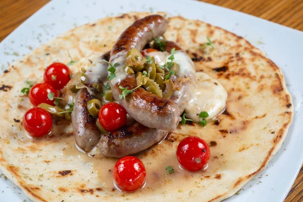 Domates ve baharatlı tortillada ızgara sosis.