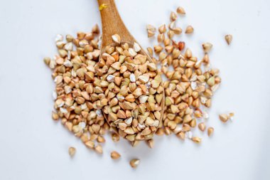 Tahta kaşıkta pişmemiş karabuğday. Beyaz arka planda premium karabuğday homurdanır
