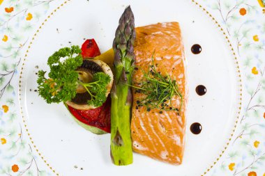 Sebzeli somon filetosu ve dinlenmek için gümüş ağırlığı.