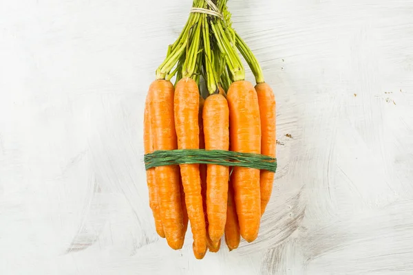 stack of carrots on a white wooden background