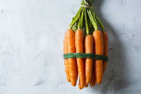 stack of carrots on a white wooden background
