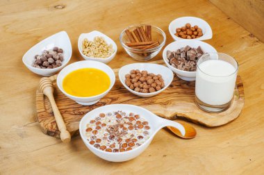 Çikolatalı gevreğin kasede, sütün kavanozda tarçın ve balın üst görüntüsü.