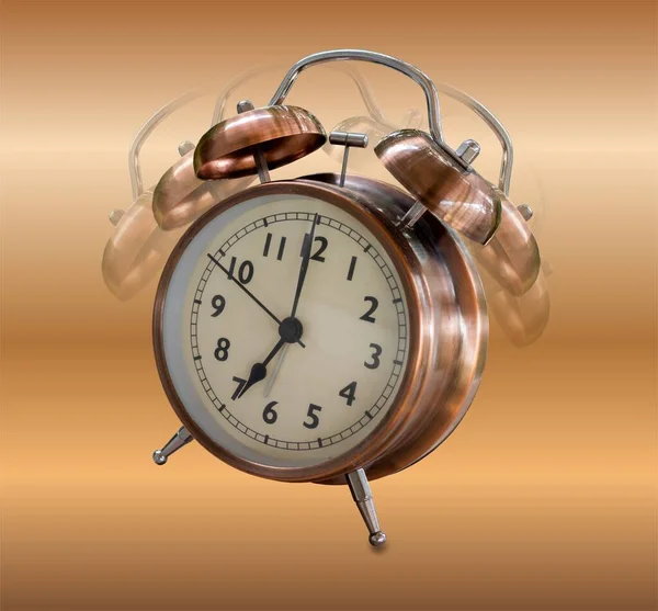Bronze ringing alarm clock in retro style. Isolated on a brown background. Close-up.  Perfect for a banner, poster or flyer.