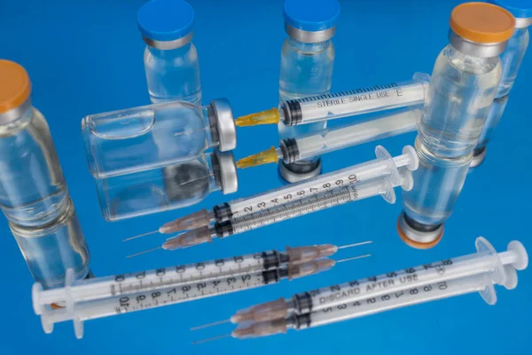 Injection ampoules with syringes and needles ready for use. Isolated on a blue background. Close-up. Interior. Macro. Selective focus. Sterilized medical equipment. Medical concept.