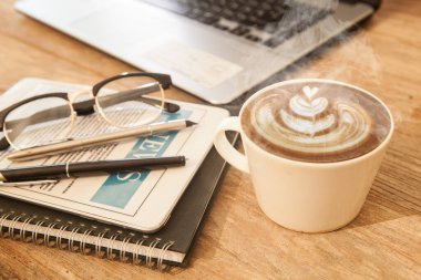 Not defteri ve kahve dolu bir ofis masası.