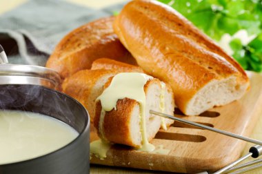 Gourmet swiss fondue dinner on a winter evening with pot of cheese fondue and forks dipping bread.
