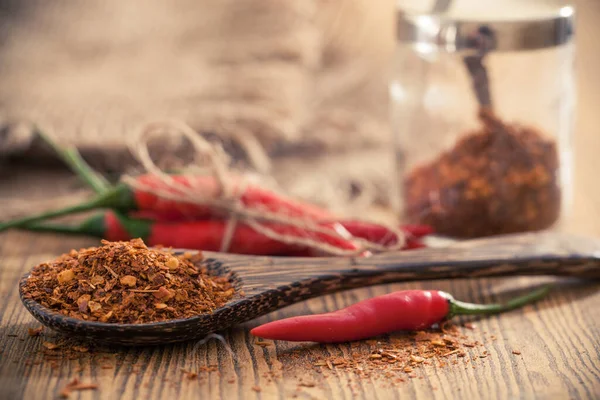 Chili powder with chili on wooden background.