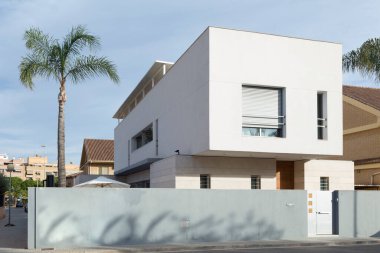 View of a house with contemporary architecture, very modern, with cubic shapes; a palm tree stands out on the side. Sagunto, Valencia, Spain clipart