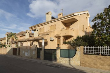 From one side of the street, view from the opposite, stately chalet-style houses with a classic style, exposed brick facade and modern construction, Sagunto, Valencia, Spain clipart