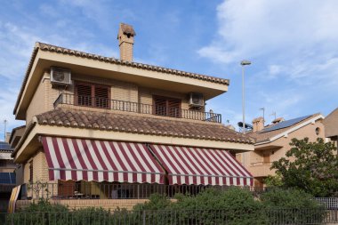 From the street, view of a house with awnings, stately chalet-style house with a classic style, exposed brick facade and modern construction, Sagunto, Valencia, Spain clipart