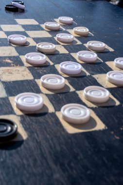 Tahta dama tahtası siyah ve beyaz parçalar arasında gergin bir maç olduğunu gösteriyor. Üzerindeki ince detaylar zamanla yapılan sayısız savaşı gözler önüne seriyor..