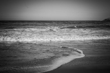 Yumuşak dalgalar, yumuşak, solgun güneş ışığı altında kumlu sahili öper. Okyanusun barışçıl sesi havayı dolduruyor. Huzurlu bir atmosfer yaratıyor. Yansıma ve rahatlama için mükemmel..