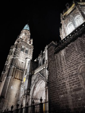 Gece gökyüzünün altında görkemli katedral kuleleri dimdik ayakta duruyor. Karmaşık tasarımları ve dokuları güzelce aydınlatılıyor. Taş duvarlar, hareketli bir şehir ortamında tarihin özünü yakalar. Toledo, İspanya.