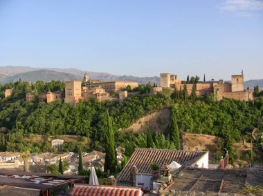 Gün batımı, canlı ağaçlar ve uzak dağlarla çerçevelenmiş Granada 'daki tarihi Alhambra' nın üzerine gökyüzünü resmediyor. Huzur içinde antik mimarinin güzelliğini gözler önüne seriyor..