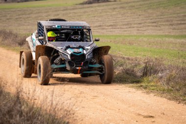 Ben Maverick İki sürücüsü bir rali aracıyla engebeli bir yolda ilerleyebilirim. Manzara, açık gökyüzünün altında yuvarlanan tepeler ve yeşil tarlalar, off-road yarışlarının heyecanını yakalıyor..