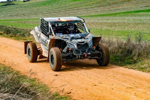 Ben Maverick 'in güçlü off-road aracı, açık mavi gökyüzünün altındaki yeşil alanlarla çevrili engebeli bir toprak yolda ilerleyebilirim. Sürücü dikkatli bir şekilde direksiyonun arkasındaki toz bulutuna odaklanır..