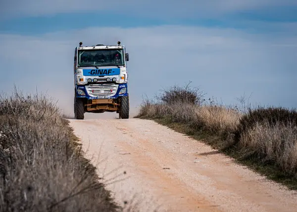DAF 'ın güçlü off-road kamyonu kuru otlar ve çalılarla çevrili tozlu toprak bir yolda ilerliyor. Açık gökyüzü, gün ışığında sakin kırsal atmosfere katkı sağlar..