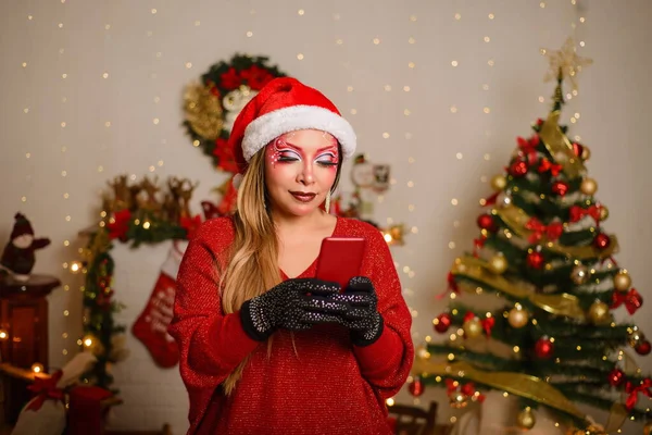 携帯電話にクリスマスのファンタジーメイクの若い女性 クリスマスの背景 — ストック写真
