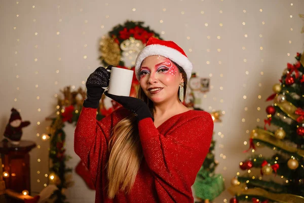 白いマグカップを持ってクリスマスファンタジーメイクを持つ若い女性 マグカップに焦点を当てます クリスマスの背景 — ストック写真
