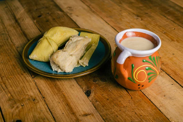 Tamales de elote ve atole tahta bir masada. Tipik Meksika yemekleri..
