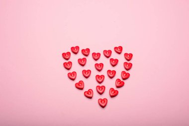 Pembe arka planda küçük kalplerden yapılmış kalp şekli. Aşk kavramı.