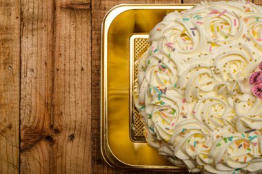 Kek, ahşap bir masada tereyağı kremalı çiçeklerle süslenmiş..