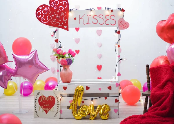Kissing booth in photo studio for children\'s photo shoot. Photo studio decorated with balloons and hearts.