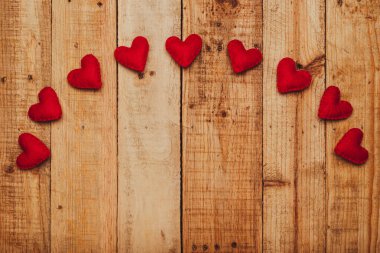 Group of hearts made of felt on wooden table forming an arch. Valentine's day background.