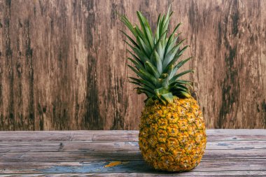 Ripe pineapple on wooden table. Ripe fruit with wood background.