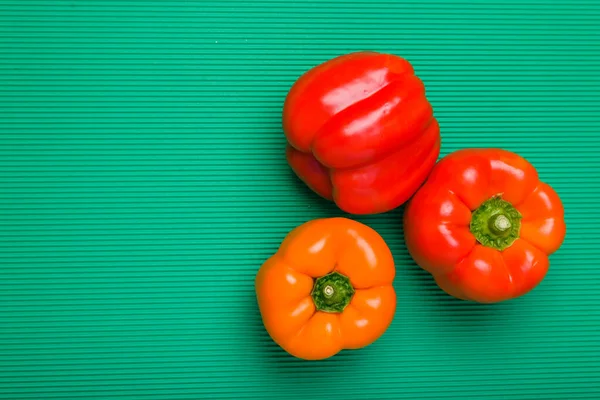 Group of bell peppers of different colors on green background. Bell peppers of different colors.