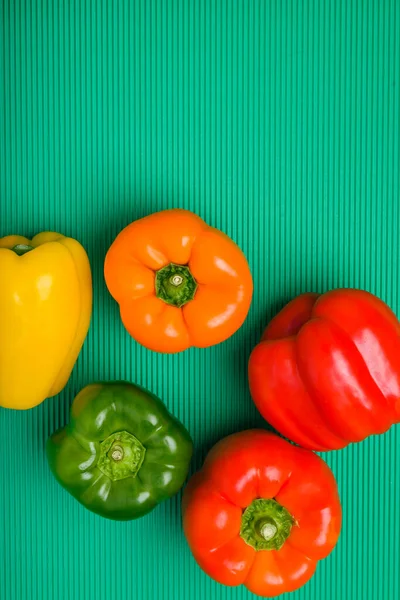 Group of bell peppers of different colors on green background. Bell peppers of different colors.