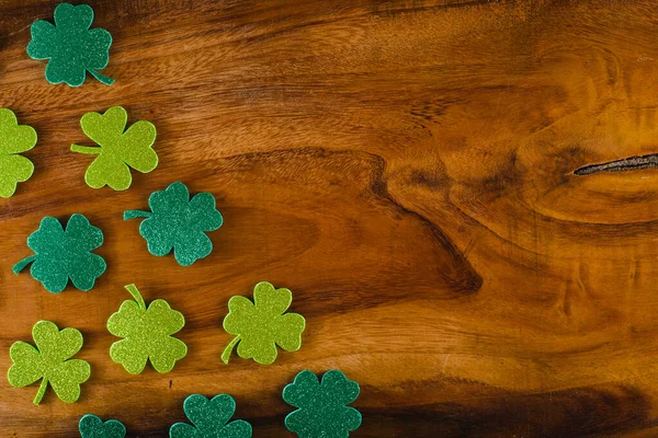 Three-leaf and four-leaf clover made of glitter material on wooden table with copy space. Saint Patrick's Day background.