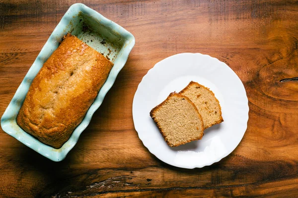 stock image Homemade sponge cake in blue ceramic mold on wooden table. Sliced Pound cake.