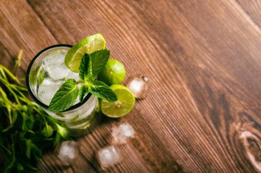 Mojito, ahşap bir masada limon ve nane şekeriyle süslenmiş kokteyl. Saman yok..