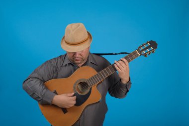 Şapka takan ve gitar çalan bir adamın stüdyo portresi