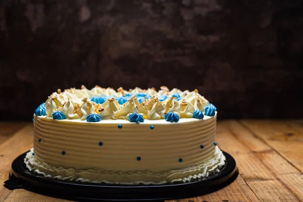 ブルークリームチーズの花と割れたくるみで飾られたケーキ 木製のテーブルの上のケーキ — ストック写真