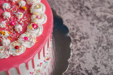 Çimento masasında pembe kremayla süslenmiş çok renkli bir pasta..