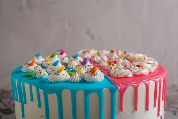 セメントテーブルの上に青とピンクのアイシングで飾られた非常にカラフルなケーキ — ストック写真