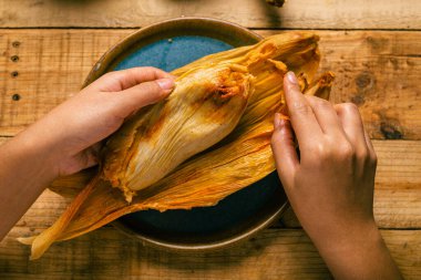 Elleriyle tamale açan biri. Tamale, tipik Meksika yemeği..