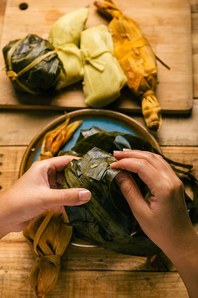 Elleriyle tamale açan biri. Tamale, tipik Meksika yemeği..