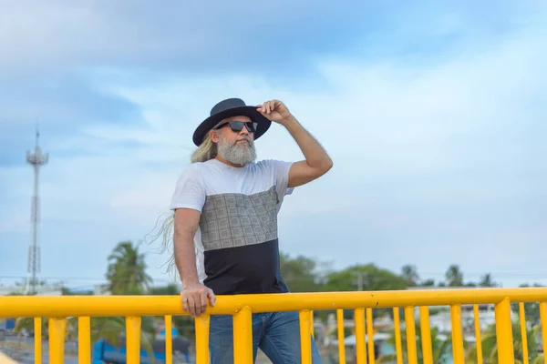 Μακρυμάλλης Γκριζομάλλης Άντρας Μαύρο Καπέλο Πεζοδρομημένη Γέφυρα Θέα Την Πόλη — Φωτογραφία Αρχείου