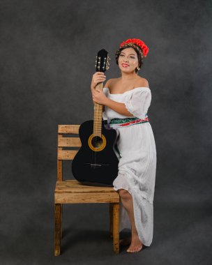 Gitarlı beyaz elbiseli Meksikalı kadın. Stüdyo resmi.