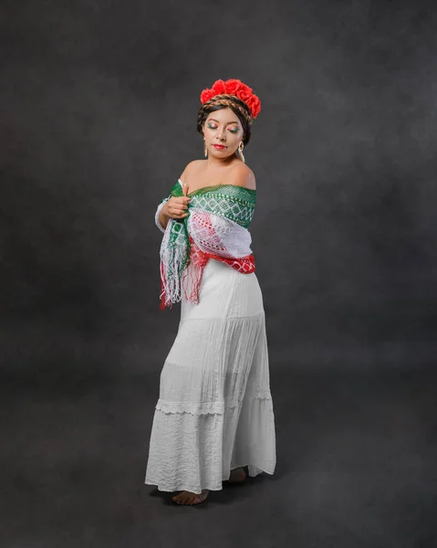 Mexican woman with white dress and tricolor scarf. Full length female portrait in studio of Mexican woman with scarf with the colors of the Mexican flag.