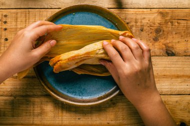 Elleriyle tamale açan biri. Tamale, tipik Meksika yemeği..