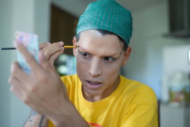 Çift cinsiyetli olmayan genç insan travesti makyajı yapıyor..