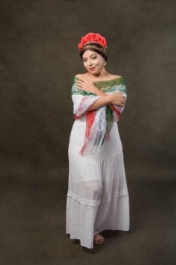 Mexican woman with white dress and tricolor scarf. Full length female portrait in studio of Mexican woman with scarf with the colors of the Mexican flag.