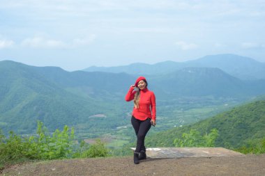 Arkasındaki tepelerle gülümseyen bir kadın..