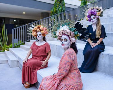 Kadınlar katrinas olarak uydurulmuş. Ölüler günü ve Cadılar Bayramı makyajı. Üç kadının açık hava grup portresi